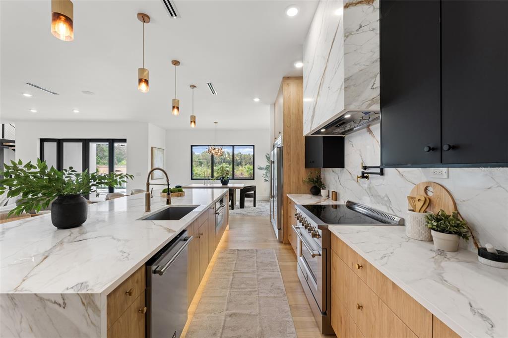 A modern kitchen features wood and black cabinetry, marble countertops, and a large center island — 12870 N ARMENIA AVENUE, TAMPA, FL