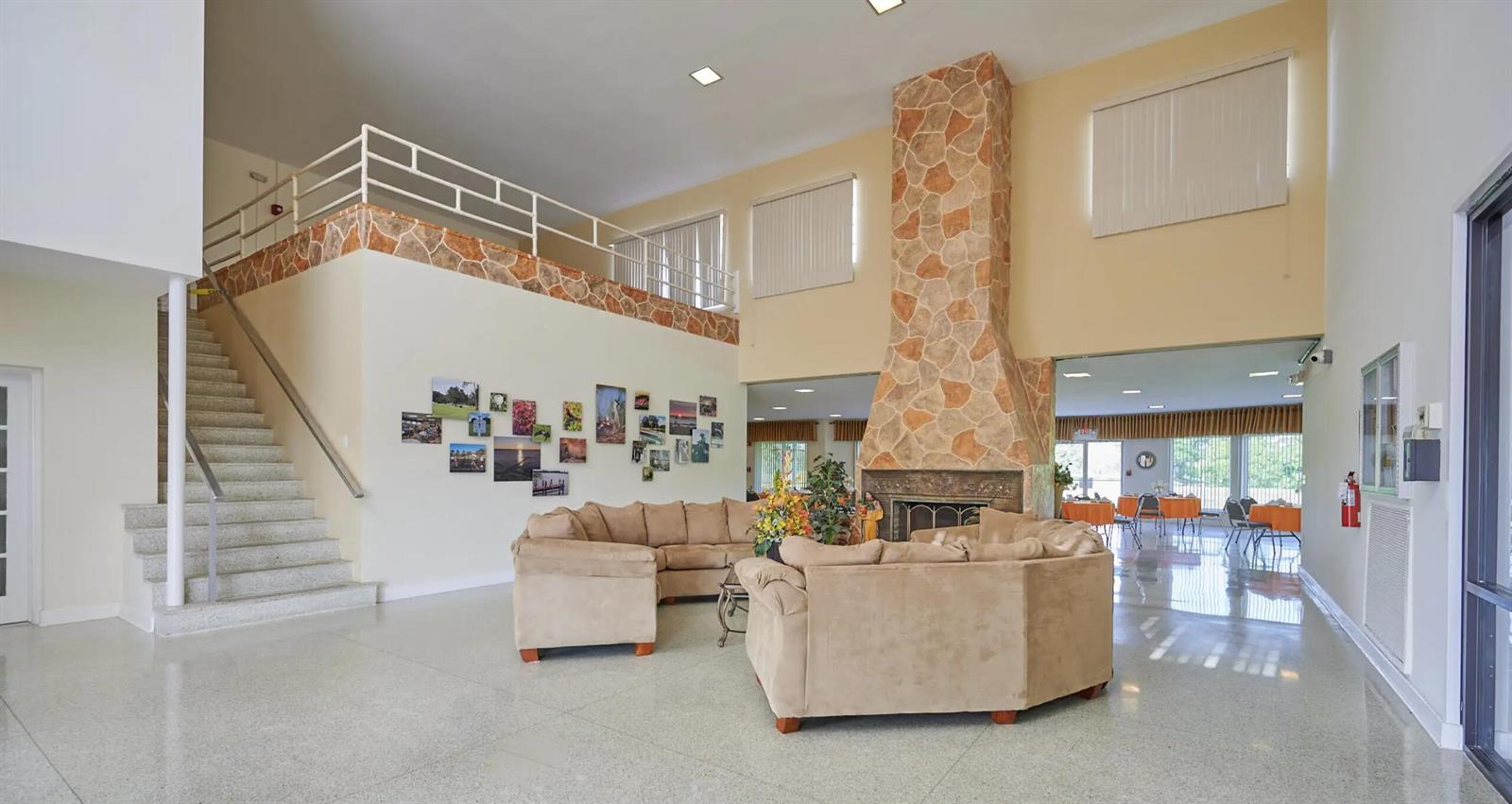 A spacious lobby features a stone fireplace, beige sectional sofas, and a staircase to a balcony — 1015 Calendula Drive, FL 33855, FL