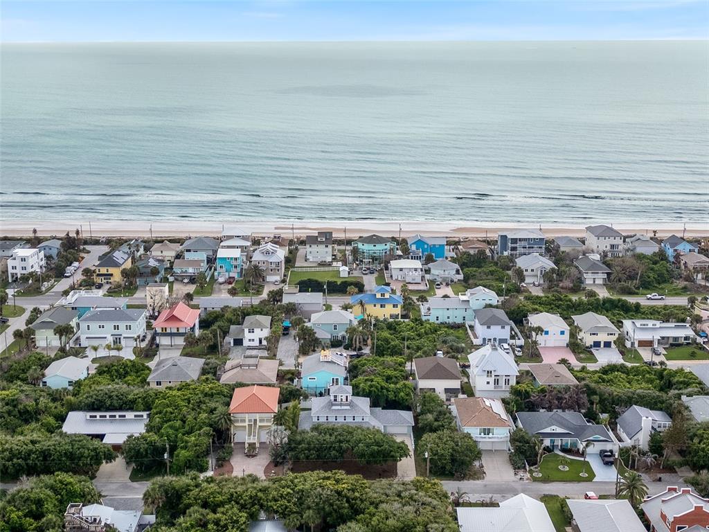 An aerial view shows a coastal neighborhood with numerous houses situated near the ocean beach — 6325 RIVER ROAD, NEW SMYRNA BEACH, FL