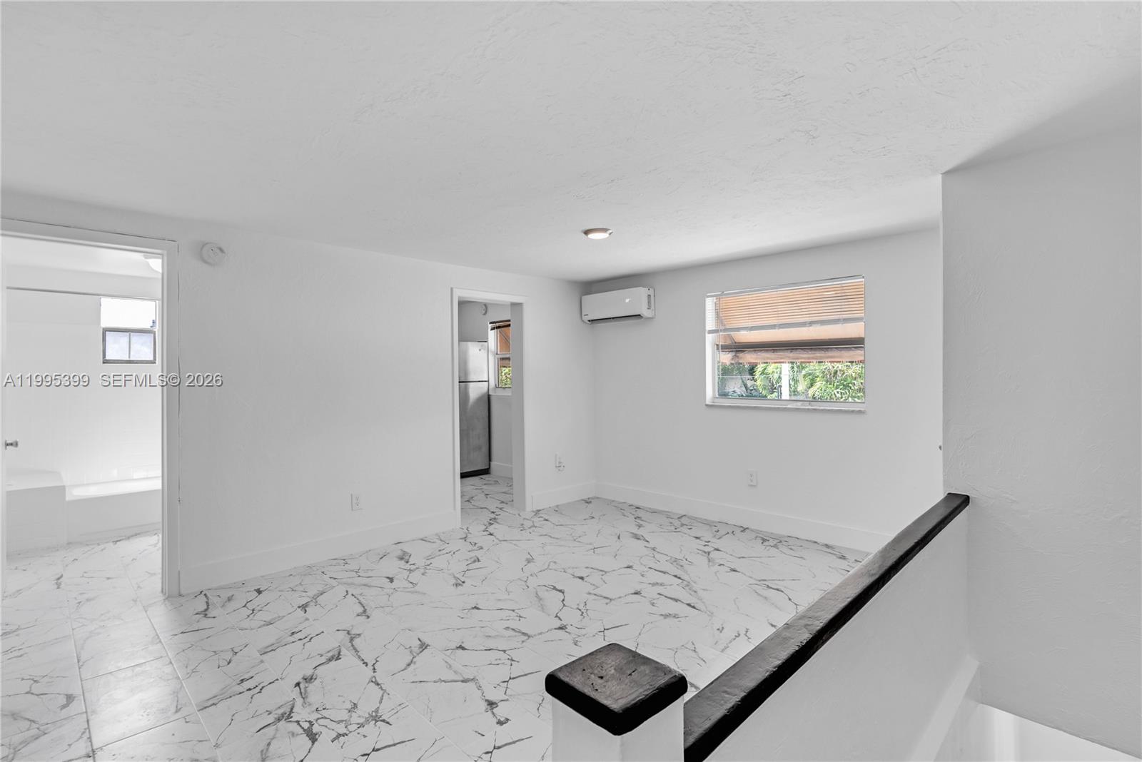 A room with white marble-patterned tile flooring, a window, and a wall-mounted air conditioner — 56 NW 62nd St # 2, Miami FL 33150, MIAMI, FL