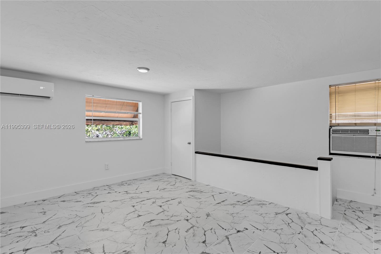 A room with white walls, marble-patterned tile flooring, a window, and a wall-mounted air conditioner — 56 NW 62nd St # 2, Miami FL 33150, MIAMI, FL