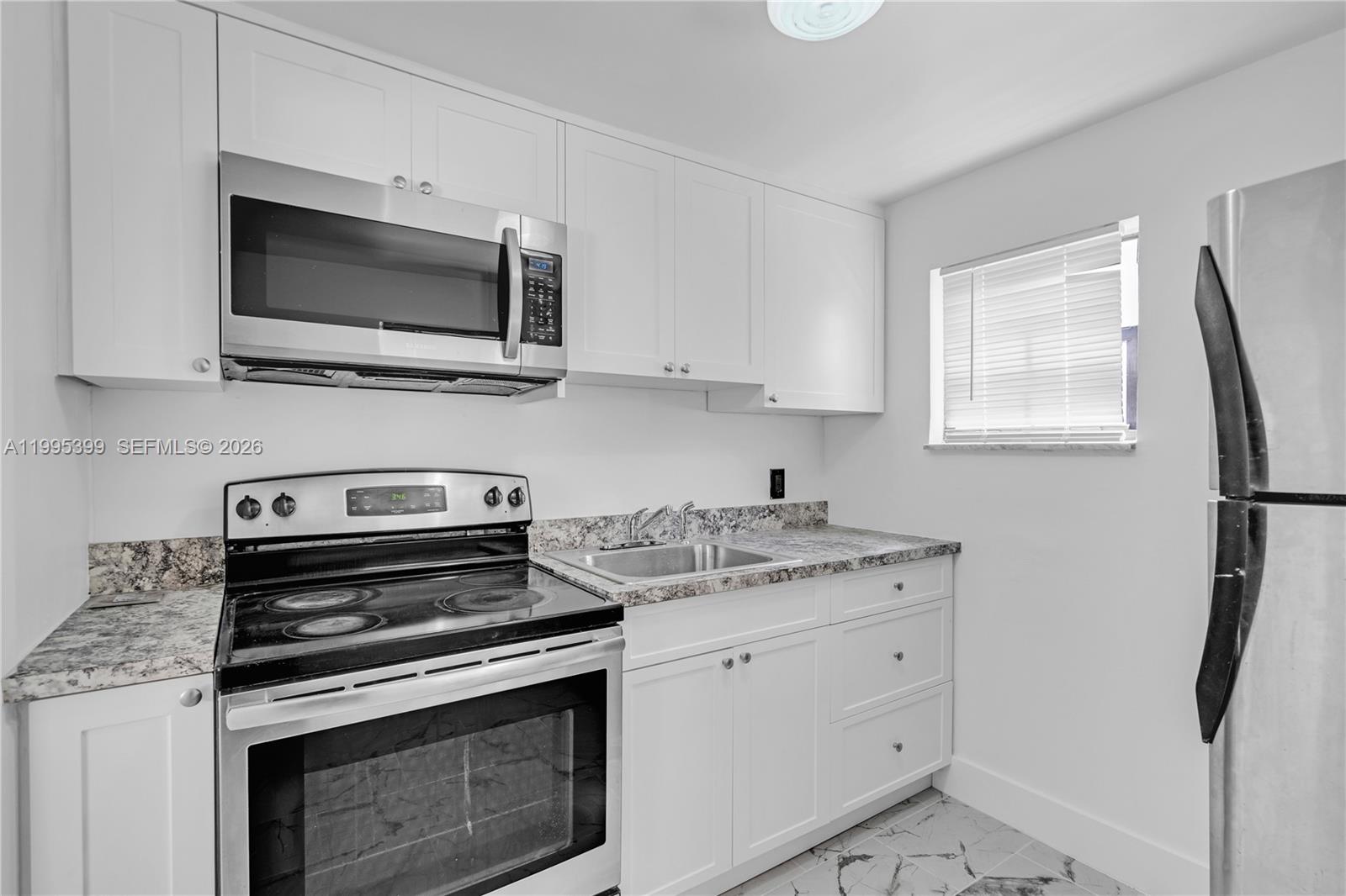 A kitchen features white cabinets, stainless steel appliances, and granite countertops — 56 NW 62nd St # 2, Miami FL 33150, MIAMI, FL