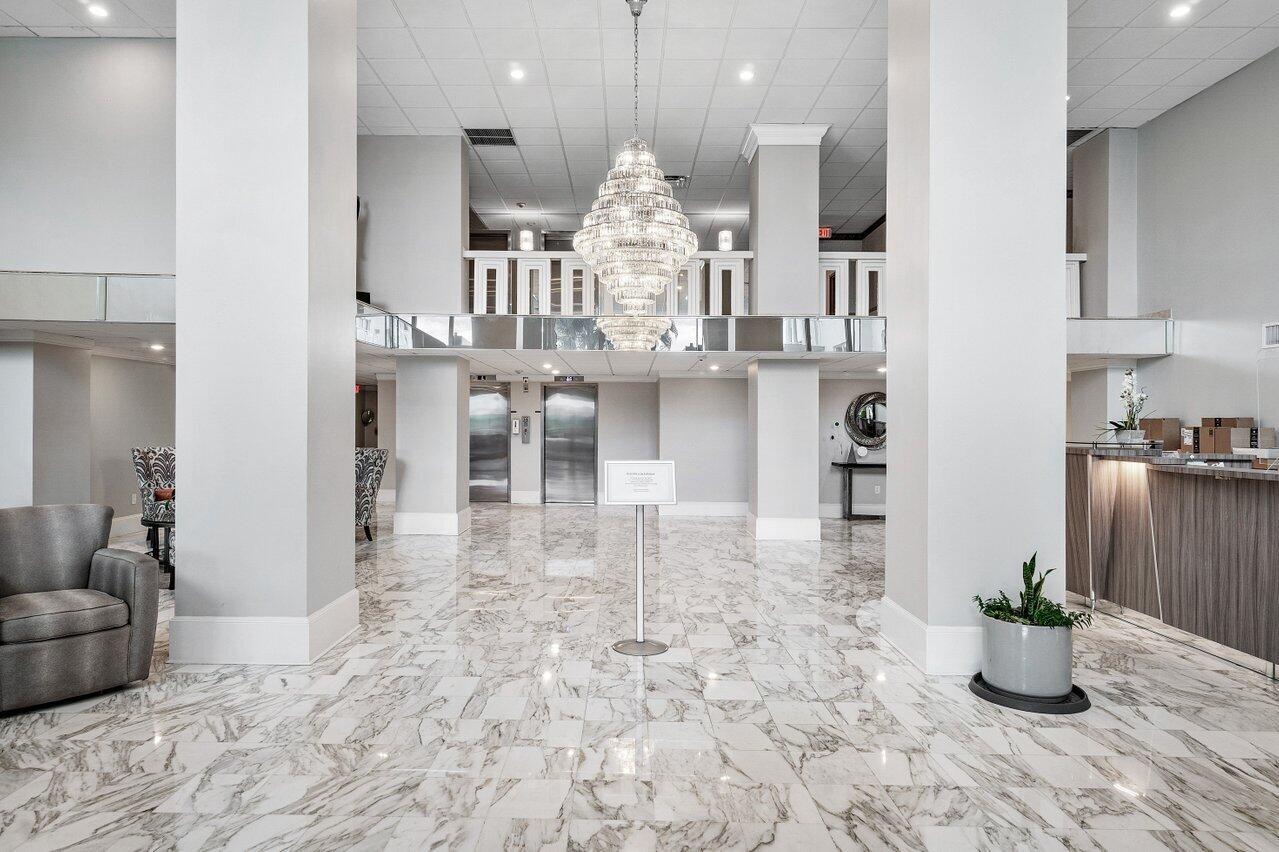 A bright hotel lobby features a large crystal chandelier, marble flooring, and two elevators — 3450 S Ocean Boulevard # 5010, Palm Beach FL 33480, PALM BEACH, FL