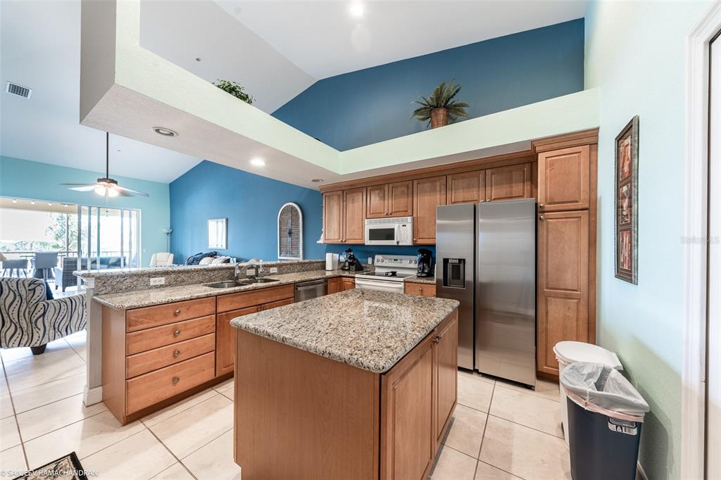 A kitchen with granite countertops, wooden cabinets, stainless steel appliances, and a central island — 3228 PURPLE MARTIN DRIVE DRIVE UNIT 125, PUNTA GORDA, FL