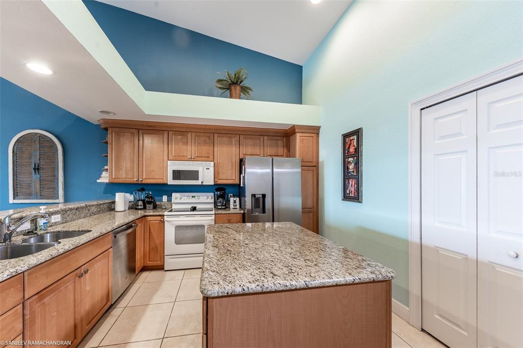 A kitchen features wood cabinets, granite countertops, stainless steel appliances, and a central island — 3228 PURPLE MARTIN DRIVE DRIVE UNIT 125, PUNTA GORDA, FL