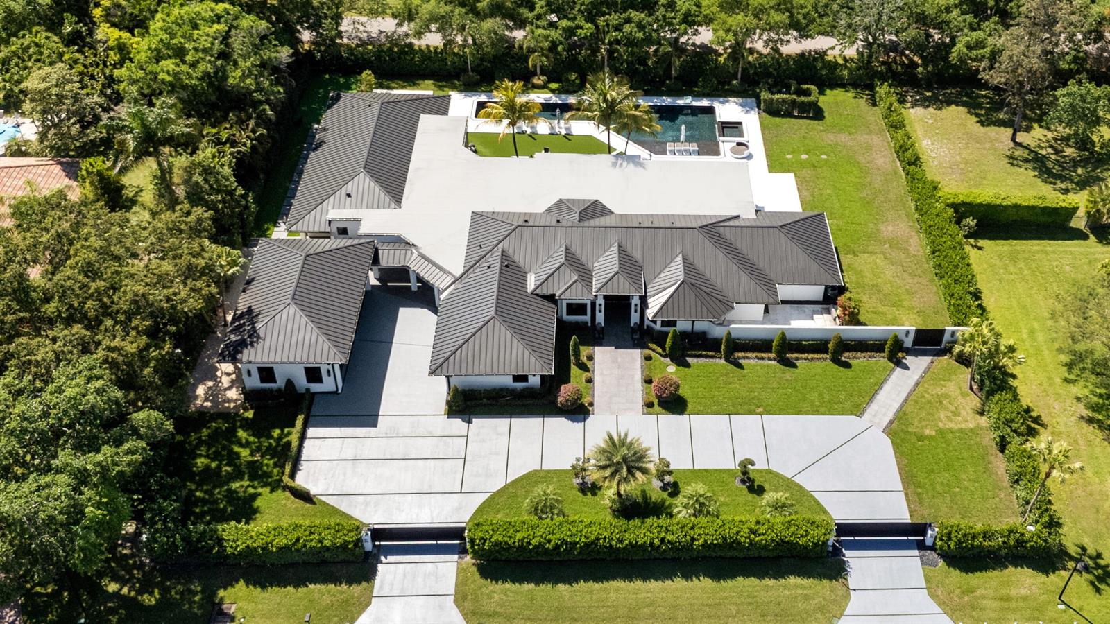 An aerial view of a modern house with a dark metal roof and swimming pool — 17872 W Fieldbrook Circle W, Boca Raton FL 33496, BOCA RATON, FL