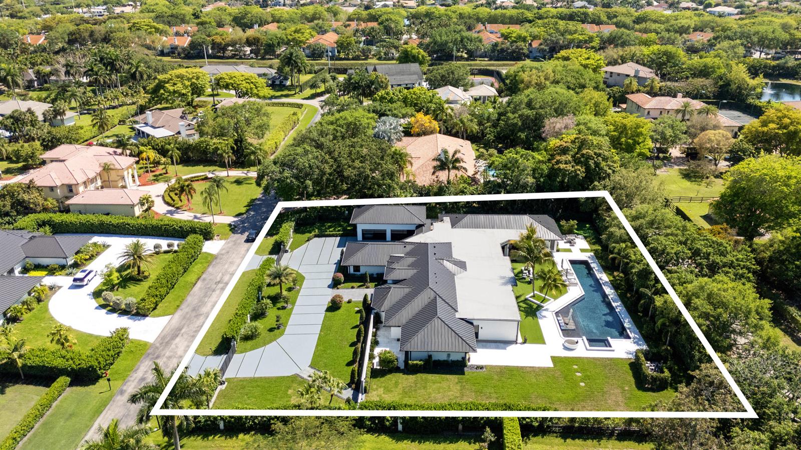 An aerial view shows a modern house with a dark metal roof and swimming pool — 17872 W Fieldbrook Circle W, Boca Raton FL 33496, BOCA RATON, FL