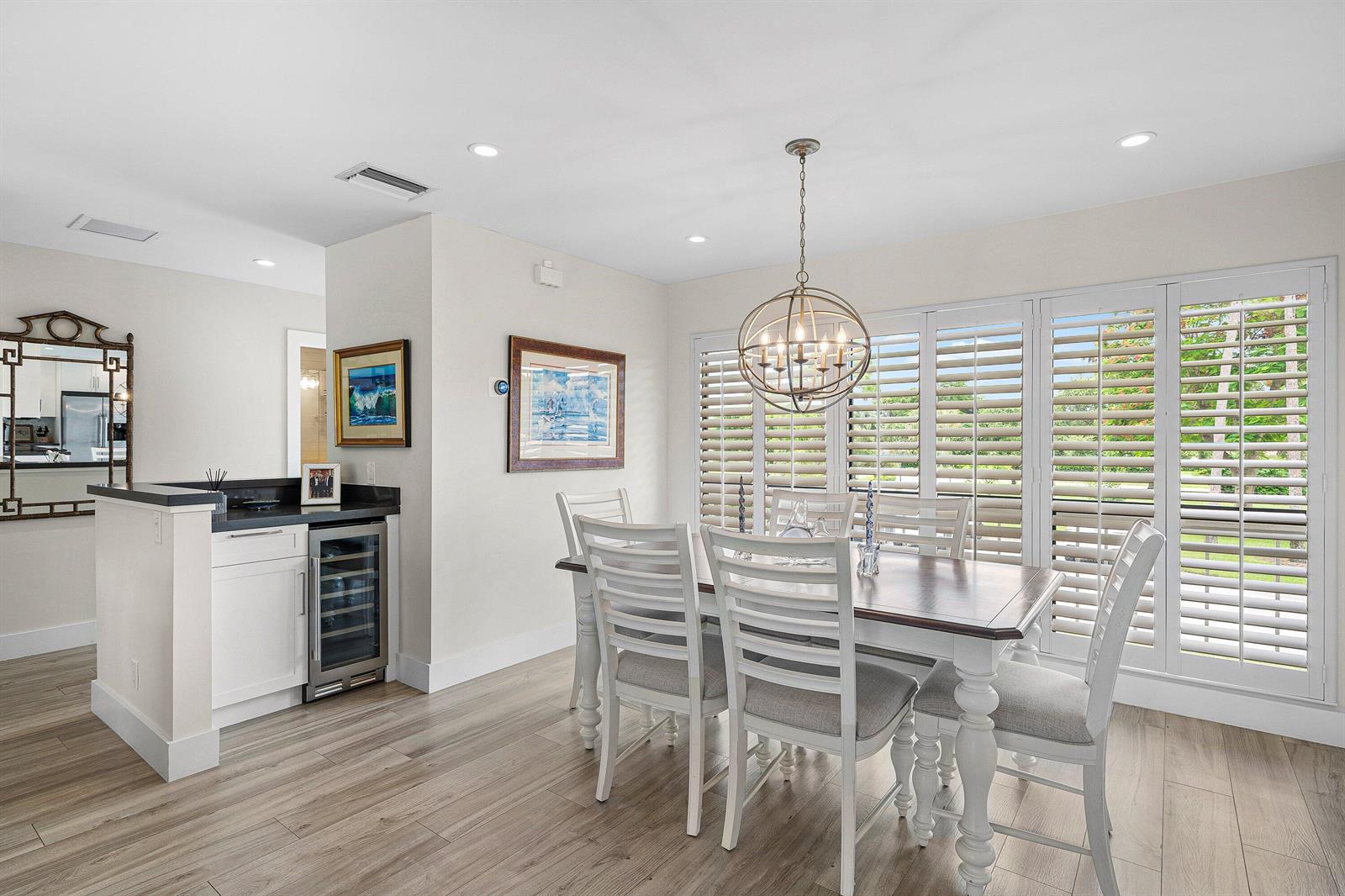 A dining room features a wooden table, white chairs, a wine cooler, and plantation shutters — 4285 B Quail Ridge Drive N, Boynton Beach FL 33436, BOYNTON BEACH, FL