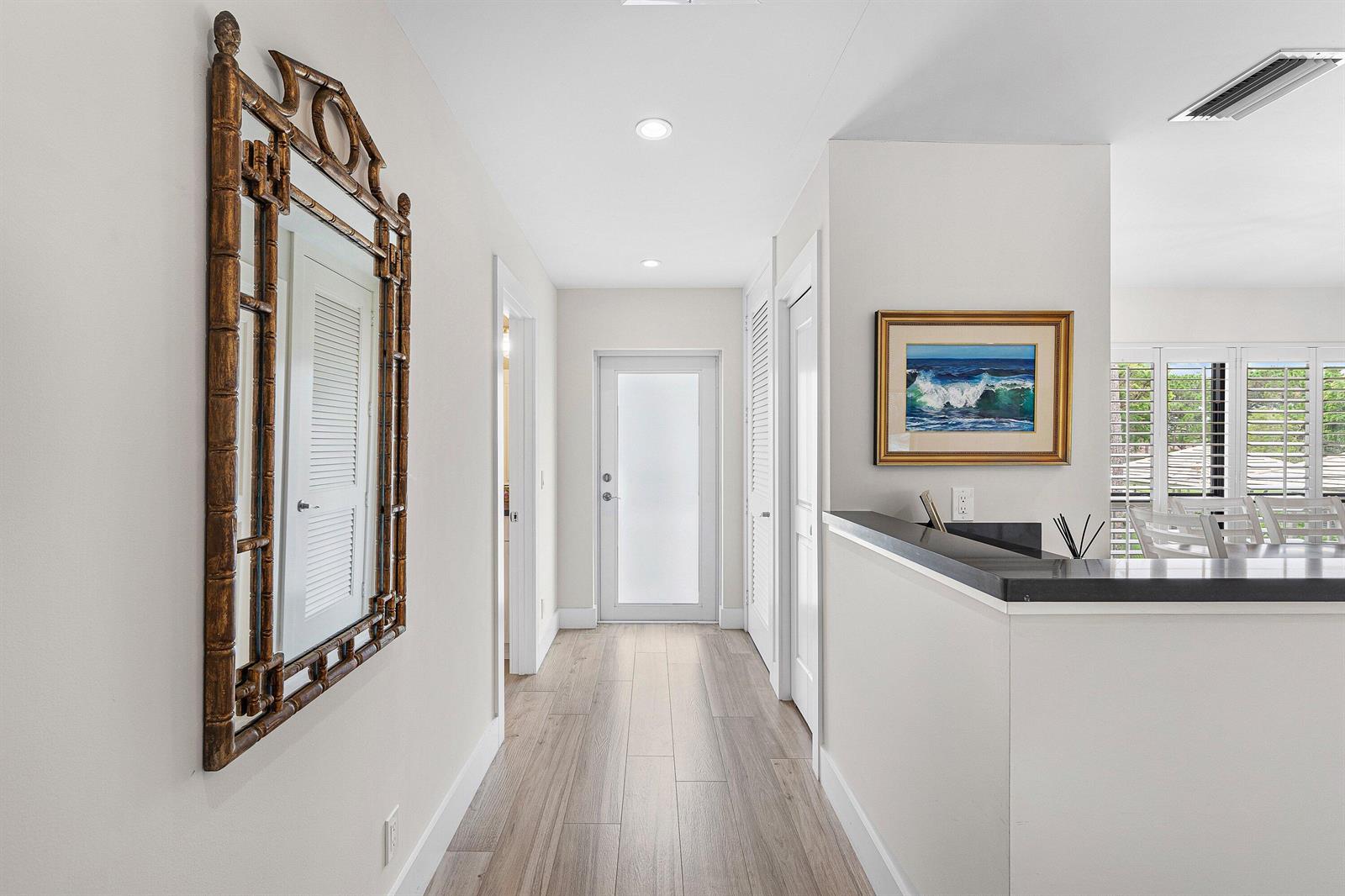A hallway with light wood-look flooring leads to a frosted glass door — 4285 B Quail Ridge Drive N, Boynton Beach FL 33436, BOYNTON BEACH, FL