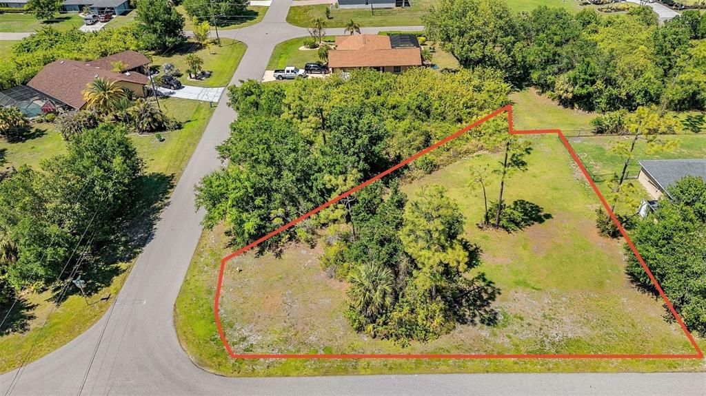 An aerial view shows a vacant, irregularly shaped residential lot outlined in red — 27298 PORTO NACIONAL DRIVE, PUNTA GORDA, FL