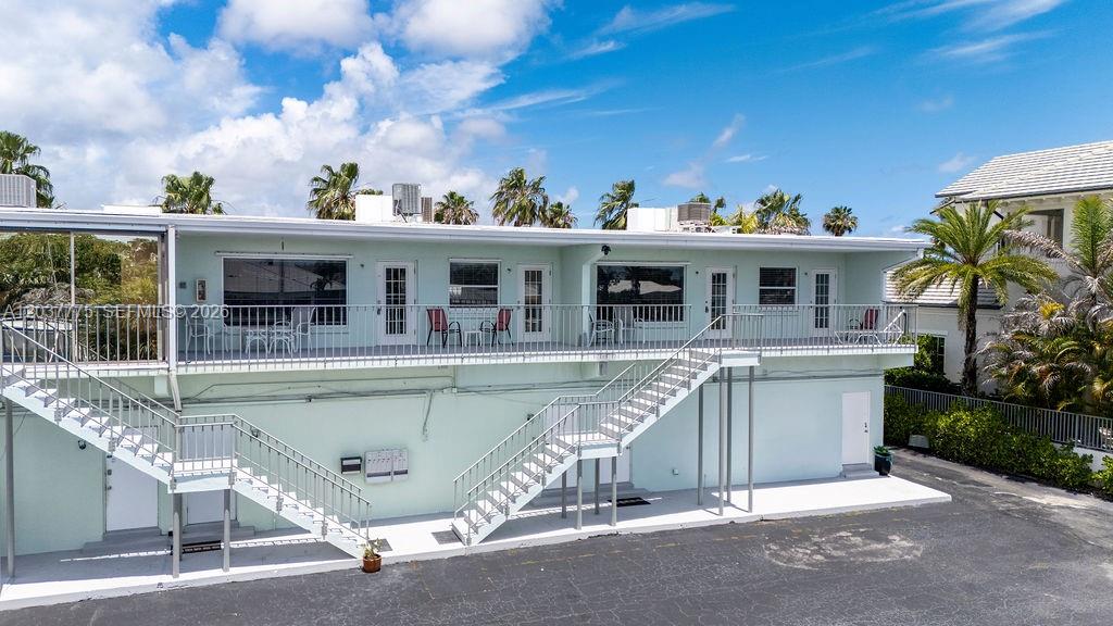 An exterior view of a two-story light green building with an outdoor staircase and balcony — 23 Royal Palm Pt # B, Vero Beach FL 32960, VERO BEACH, FL
