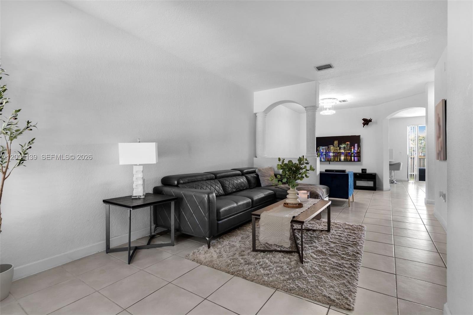 A living room features a black leather sectional, a coffee table, and a tile floor — 2583 SE 13th Ct, Homestead FL 33035, HOMESTEAD, FL