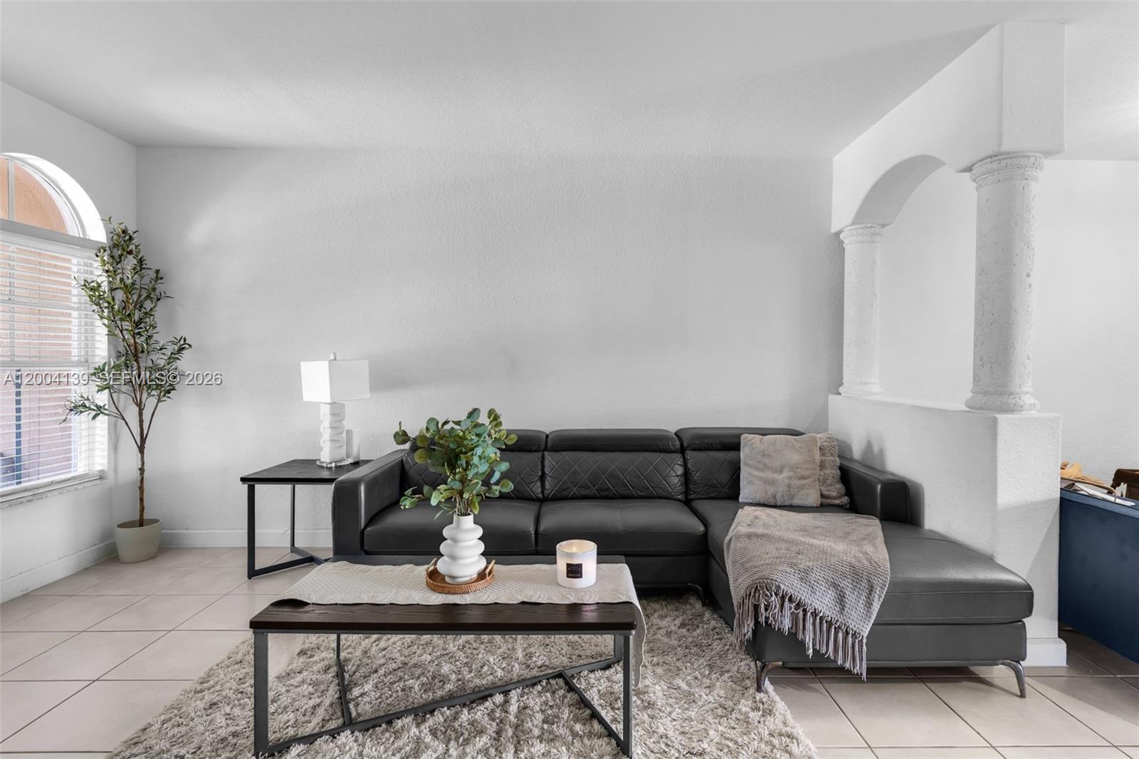 A living room features a black sectional sofa, a coffee table, and decorative columns — 2583 SE 13th Ct, Homestead FL 33035, HOMESTEAD, FL