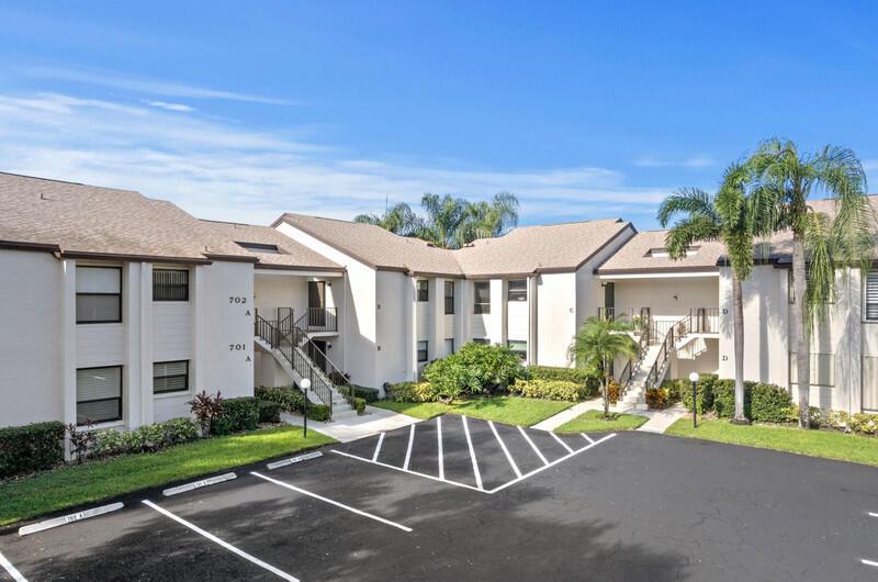 An exterior view of a multi-unit apartment complex with a parking lot in the foreground — 702 Wingfoot Drive # D, Jupiter FL 33458, JUPITER, FL