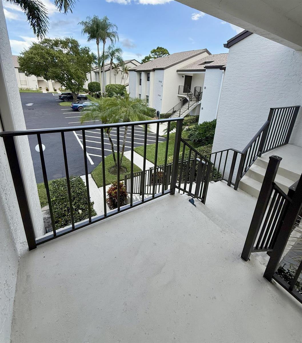 An outdoor concrete stairwell and landing with black metal railings overlooking a parking lot — 702 Wingfoot Drive # D, Jupiter FL 33458, JUPITER, FL