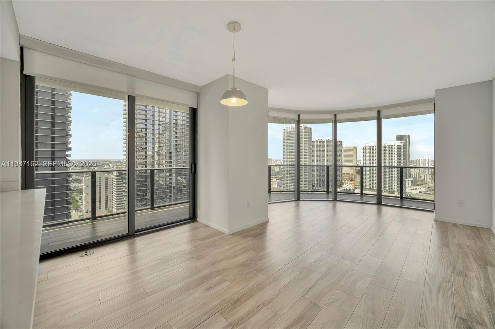 An empty room with light wood-look flooring, floor-to-ceiling windows, and a city skyline view — 801 S Miami Ave # 2909, Miami FL 33130, MIAMI, FL