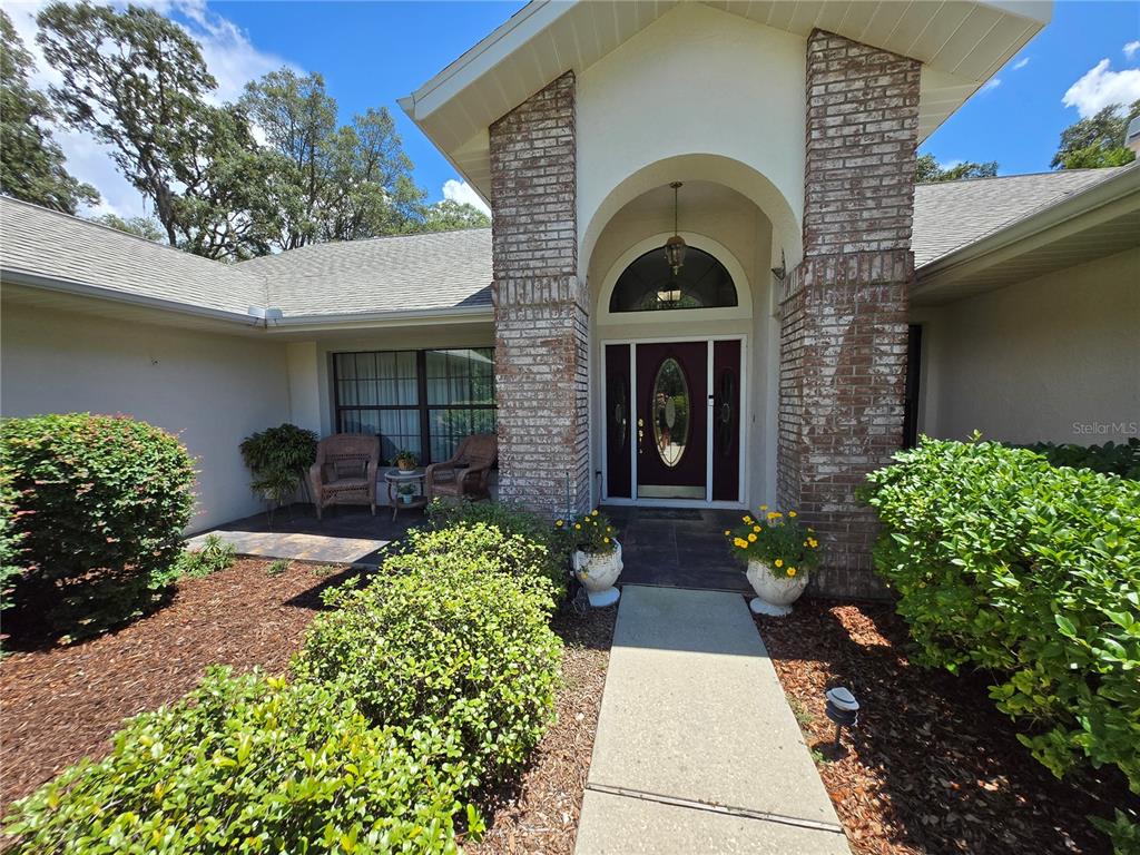 A brick-accented entryway features a dark front door with a glass insert and arched transom — 244 W MASSACHUSETTS STREET, HERNANDO, FL