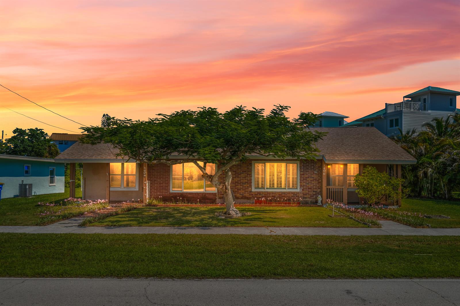 A single-story brick house with a large central tree and a sunset sky background — 1404 Binney Drive, Fort Pierce FL 34949, FORT PIERCE, FL