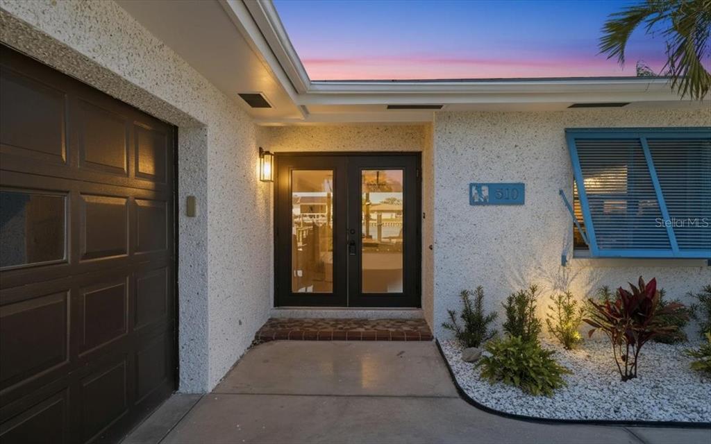 A front entryway features a dark double door, a garage, and a blue shuttered window — 510 115TH AVENUE, TREASURE ISLAND, FL