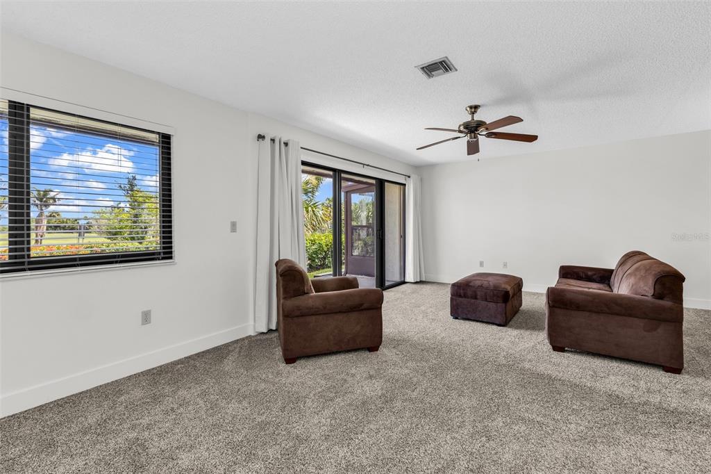A living room with gray carpet, brown furniture, a ceiling fan, and sliding glass doors — 1001 W MARION AVENUE UNIT 5, PUNTA GORDA, FL