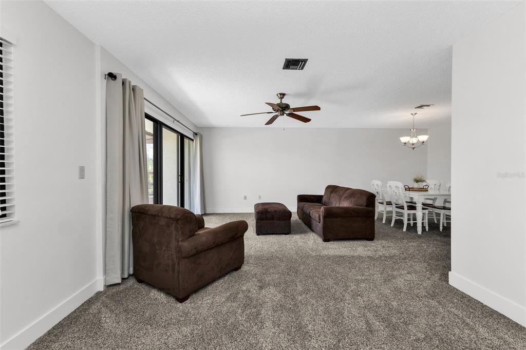 A living room with gray carpet, brown furniture, a ceiling fan, and a dining area — 1001 W MARION AVENUE UNIT 5, PUNTA GORDA, FL