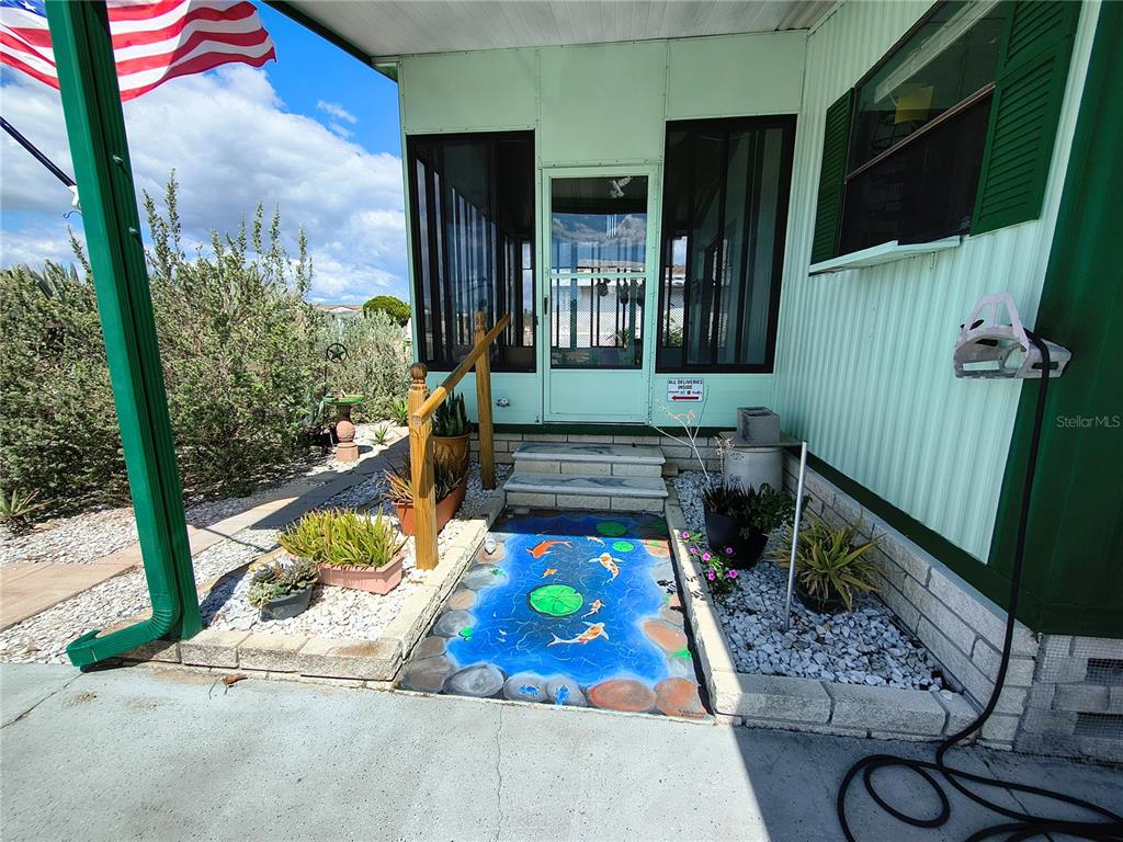 A painted koi pond mural leads to the screened-in porch of a mobile home — 7306 GRAND PINE DRIVE, HUDSON, FL