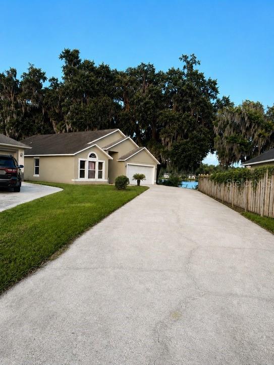 A tan house with a long driveway sits in front of large, moss-draped trees — 815 DELFINO PLACE, LAKE MARY, FL