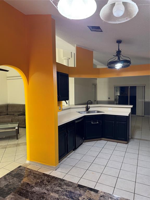 A kitchen with black cabinets and white countertops features an orange wall and tiled floors — 815 DELFINO PLACE, LAKE MARY, FL