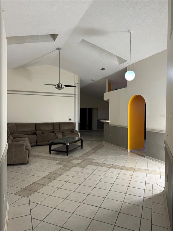 A living room with vaulted ceilings, tile flooring, a sectional sofa, and an arched doorway — 815 DELFINO PLACE, LAKE MARY, FL