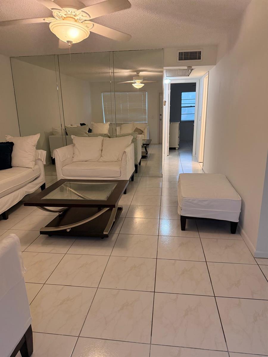 A living room features white tile floors, a glass-topped coffee table, and mirrored walls — 227 Kent N, West Palm Beach FL 33417, WEST PALM BEACH, FL