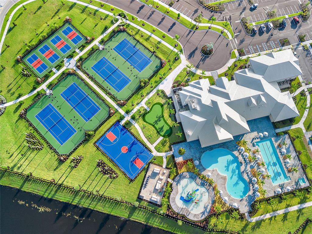 An aerial view shows a community clubhouse with a pool, sports courts, and parking lot — 15004 MISTY WATER CROSSING, LAKEWOOD RANCH, FL