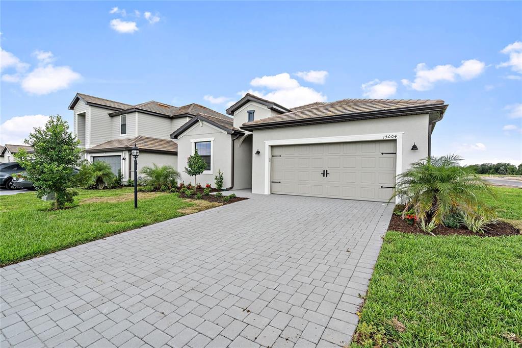 The exterior of a two-story house features a paved driveway and a two-car garage — 15004 MISTY WATER CROSSING, LAKEWOOD RANCH, FL