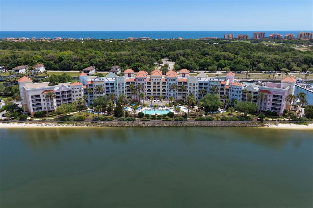 An aerial view shows a large, multi-story resort building situated along a waterfront with palm trees — 102 YACHT HARBOR DRIVE UNIT 371, PALM COAST, FL