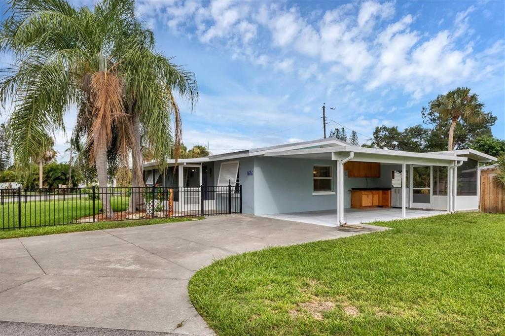 A single-story house with a concrete driveway, a carport, and a black metal fence — 1686 CHAPLINE LANE, SARASOTA, FL