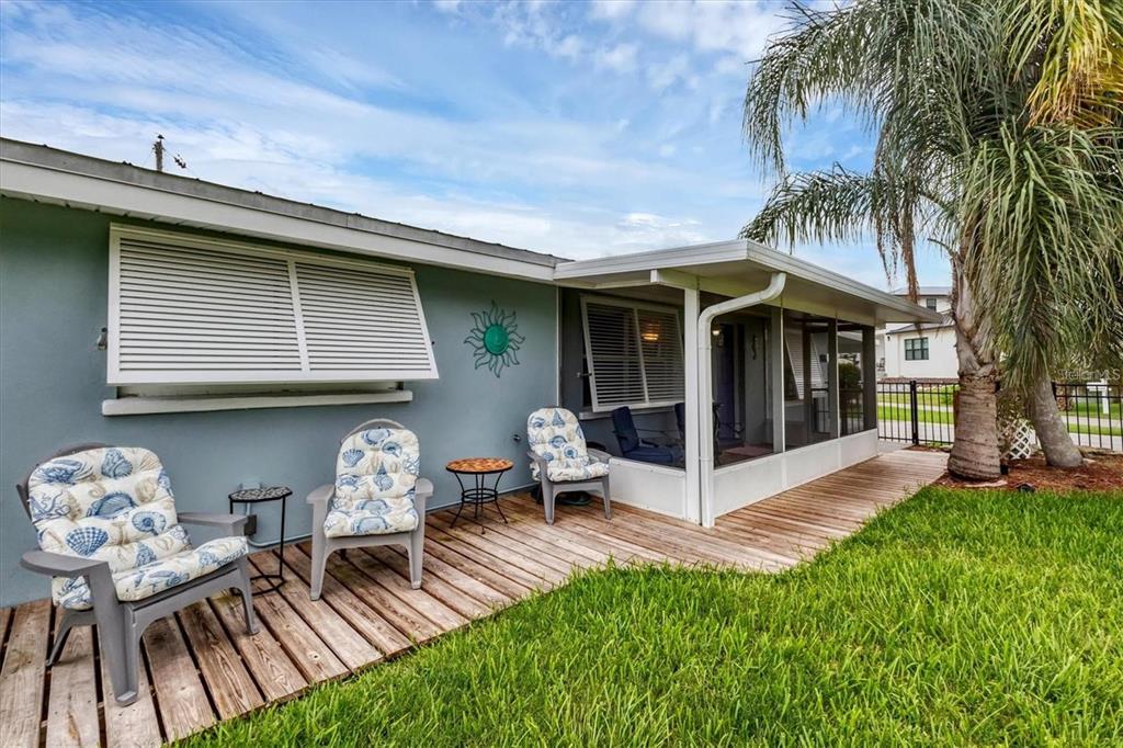 A wooden deck features three chairs with seashell cushions beside a house with a screened porch — 1686 CHAPLINE LANE, SARASOTA, FL