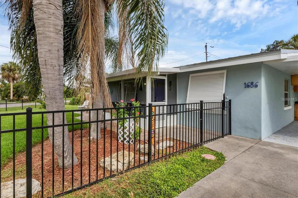 A light blue house with a fenced front porch, a palm tree, and a driveway — 1686 CHAPLINE LANE, SARASOTA, FL
