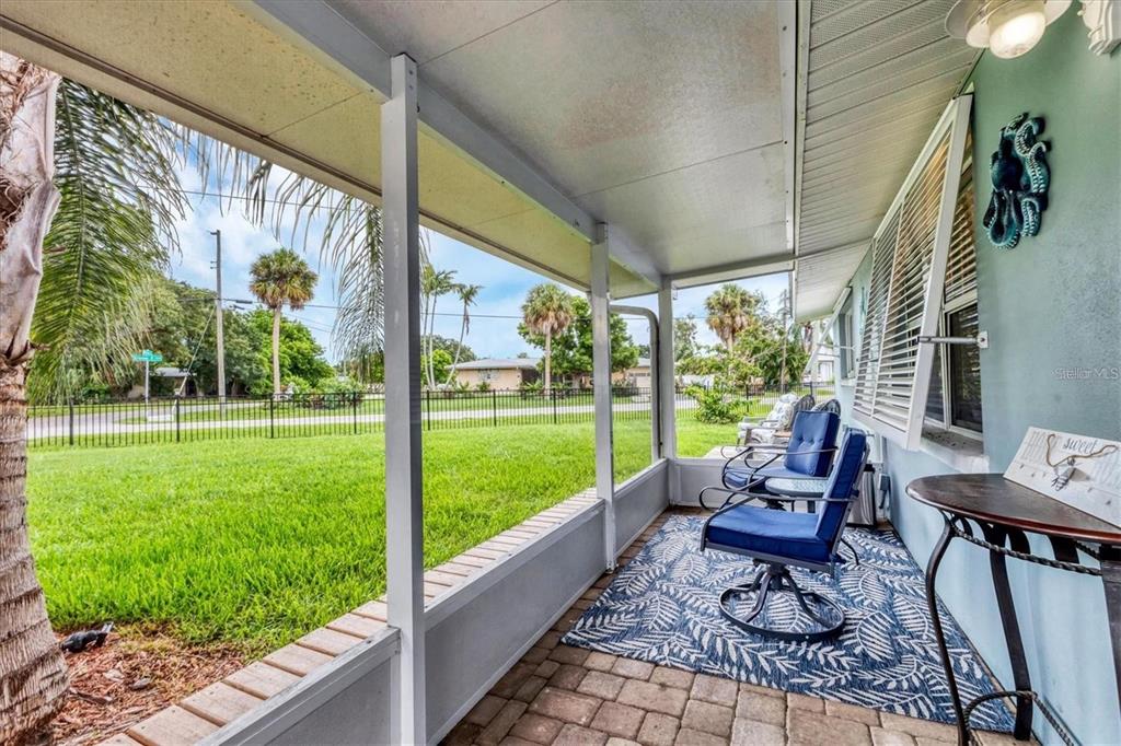 A screened-in porch features a brick floor, blue patio chairs, and a view of a lawn — 1686 CHAPLINE LANE, SARASOTA, FL