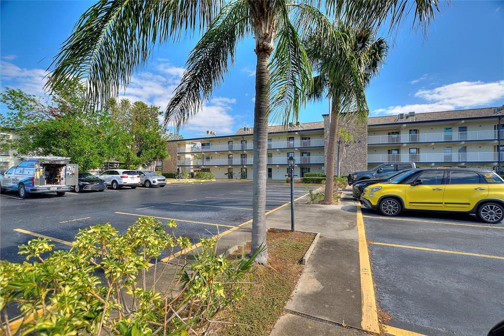 A parking lot with several cars sits in front of a multi-story apartment building — 6100 12TH STREET S UNIT 221, ST PETERSBURG, FL