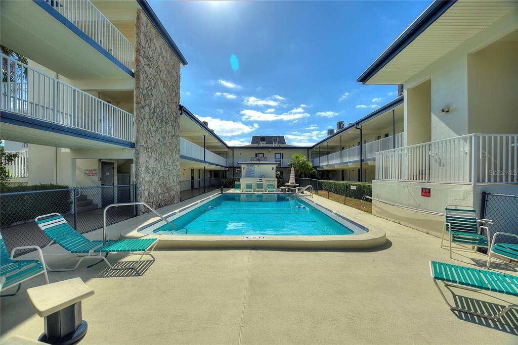 An outdoor swimming pool is surrounded by a concrete deck and two-story apartment buildings — 6100 12TH STREET S UNIT 221, ST PETERSBURG, FL