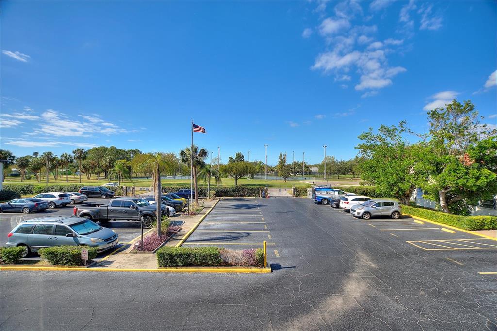 An outdoor parking lot with several parked cars and a view of a grassy field — 6100 12TH STREET S UNIT 221, ST PETERSBURG, FL