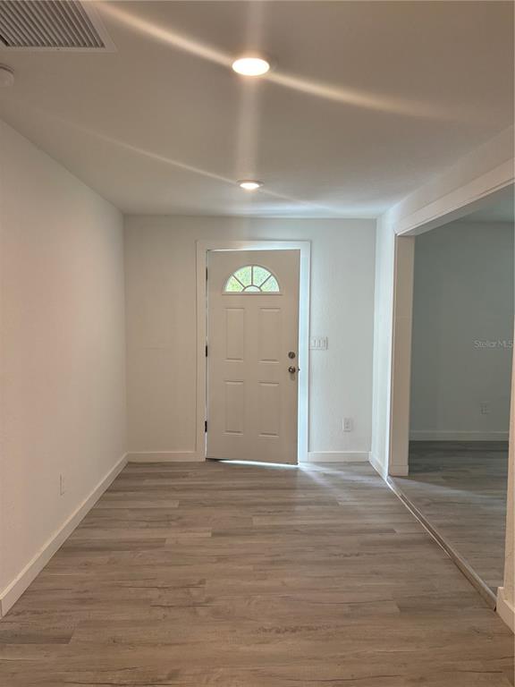 A room with light-colored wood-look flooring, white walls, and a white front door — 312 SE 49TH DRIVE, GAINESVILLE, FL