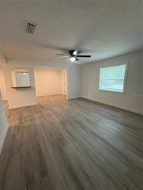 A living room features light wood-look flooring, a ceiling fan, and an open pass-through window — 312 SE 49TH DRIVE, GAINESVILLE, FL