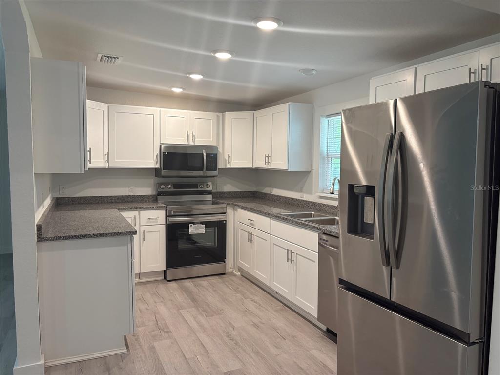 A kitchen features white cabinets, stainless steel appliances, and gray countertops — 312 SE 49TH DRIVE, GAINESVILLE, FL