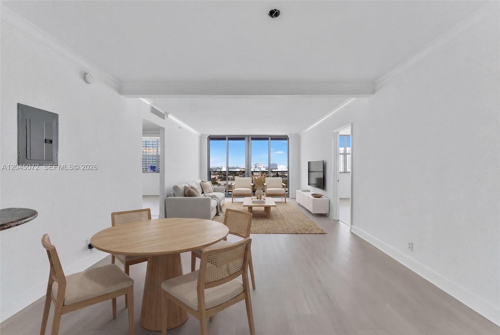 This open-concept living and dining area features light wood floors, white walls, and floor-to-ceiling windows — 401 69th St # 1201, Miami Beach FL 33141, MIAMI BEACH, FL