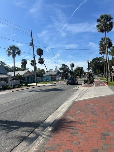 A street view shows a paved road, brick sidewalk, palm trees, and a distant church steeple — 8284 W CATRINA LANE, CRYSTAL RIVER, FL