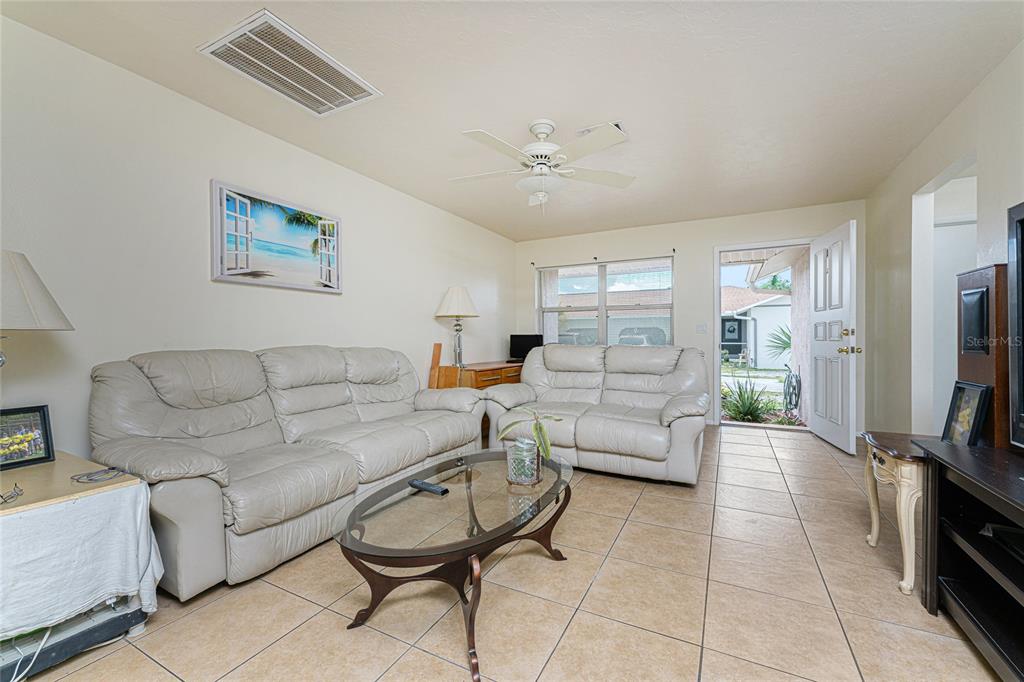 A living room features light-colored leather sofas, a glass coffee table, and tile flooring — 51 BOUNDARY BOULEVARD UNIT B, ROTONDA WEST, FL