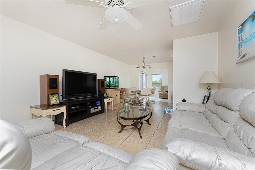 A living room features tile flooring, a white leather sofa, and a television console — 51 BOUNDARY BOULEVARD UNIT B, ROTONDA WEST, FL