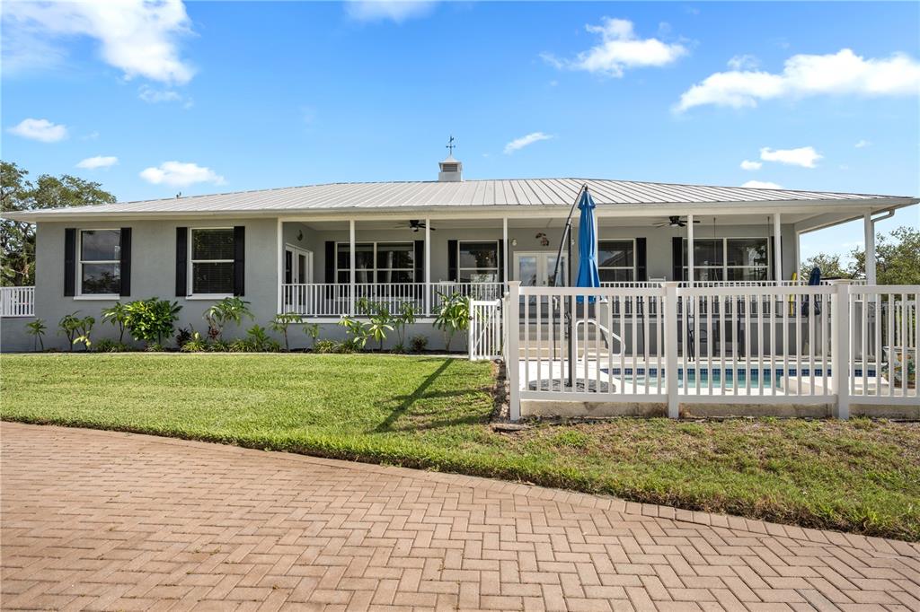 A single-story house with a metal roof, covered porch, and a fenced-in swimming pool — 310 13TH AVENUE W, PALMETTO, FL
