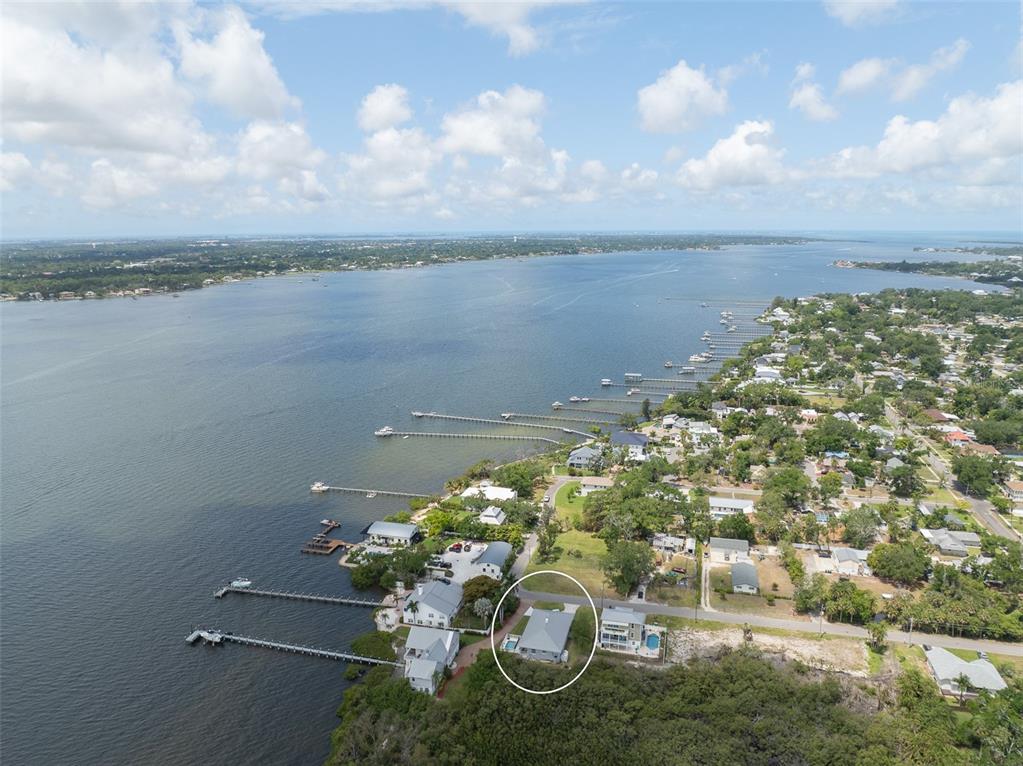 An aerial view shows a waterfront neighborhood with a circled house near the shoreline — 310 13TH AVENUE W, PALMETTO, FL