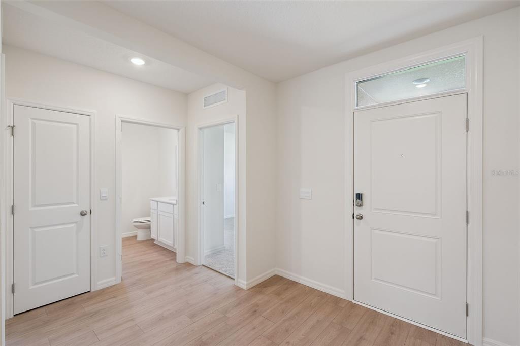 An entryway with light wood-look flooring, a white front door, and two interior doorways — 2514 DORSET COURT, ORMOND BEACH, FL